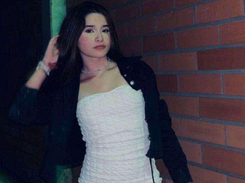 Imagem mostra uma adolescente menina com vestido branco casaco preto cabelos escuros solto fazendo pose para foto Ela usa no pulso vrias pulseiras e segura o cabelo com uma das mos A jovem morreu em acidente com scooter em Brusque no Vale do Itaja