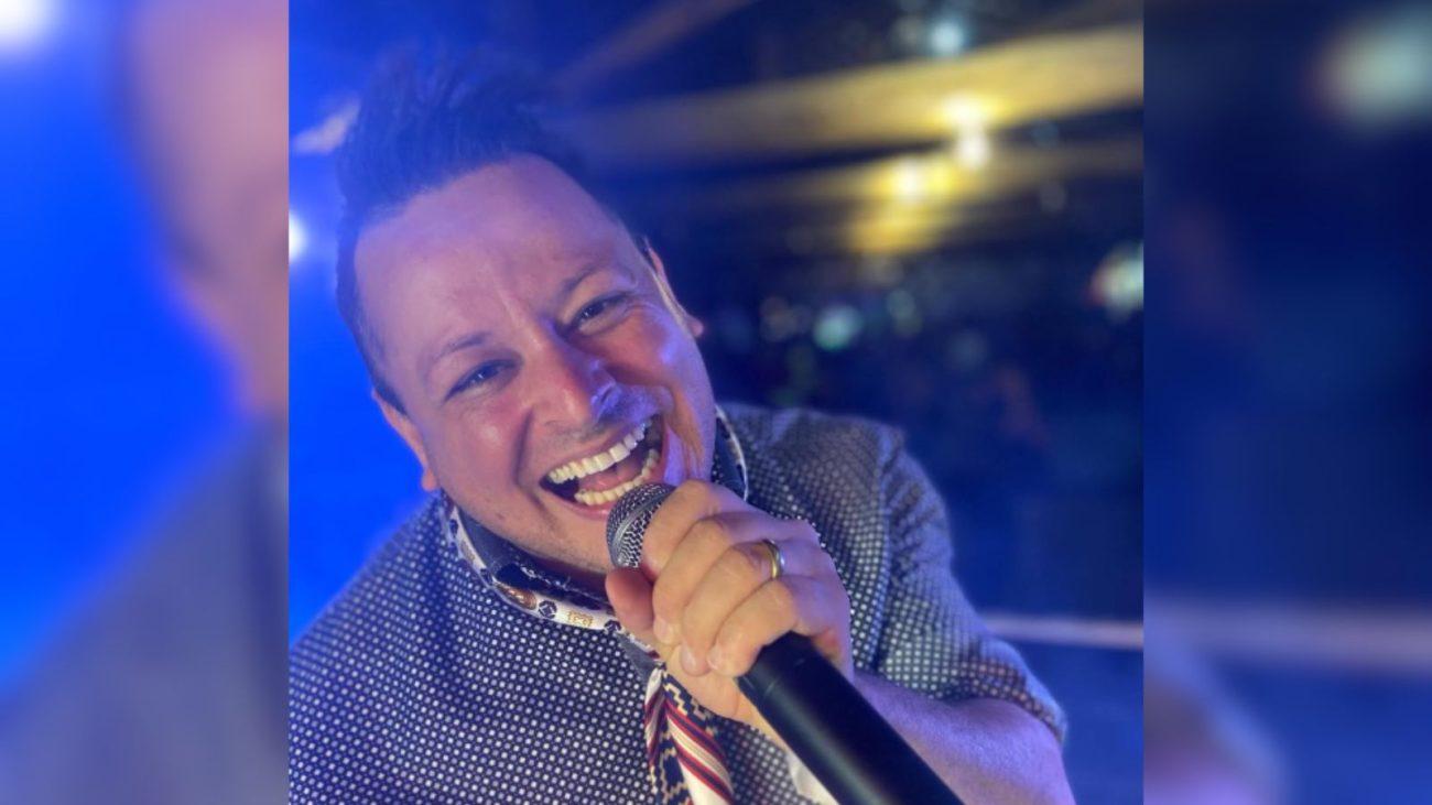 cantor sertanejo Luciano Rocha sorrindo com um microfone em mos no meio de um show